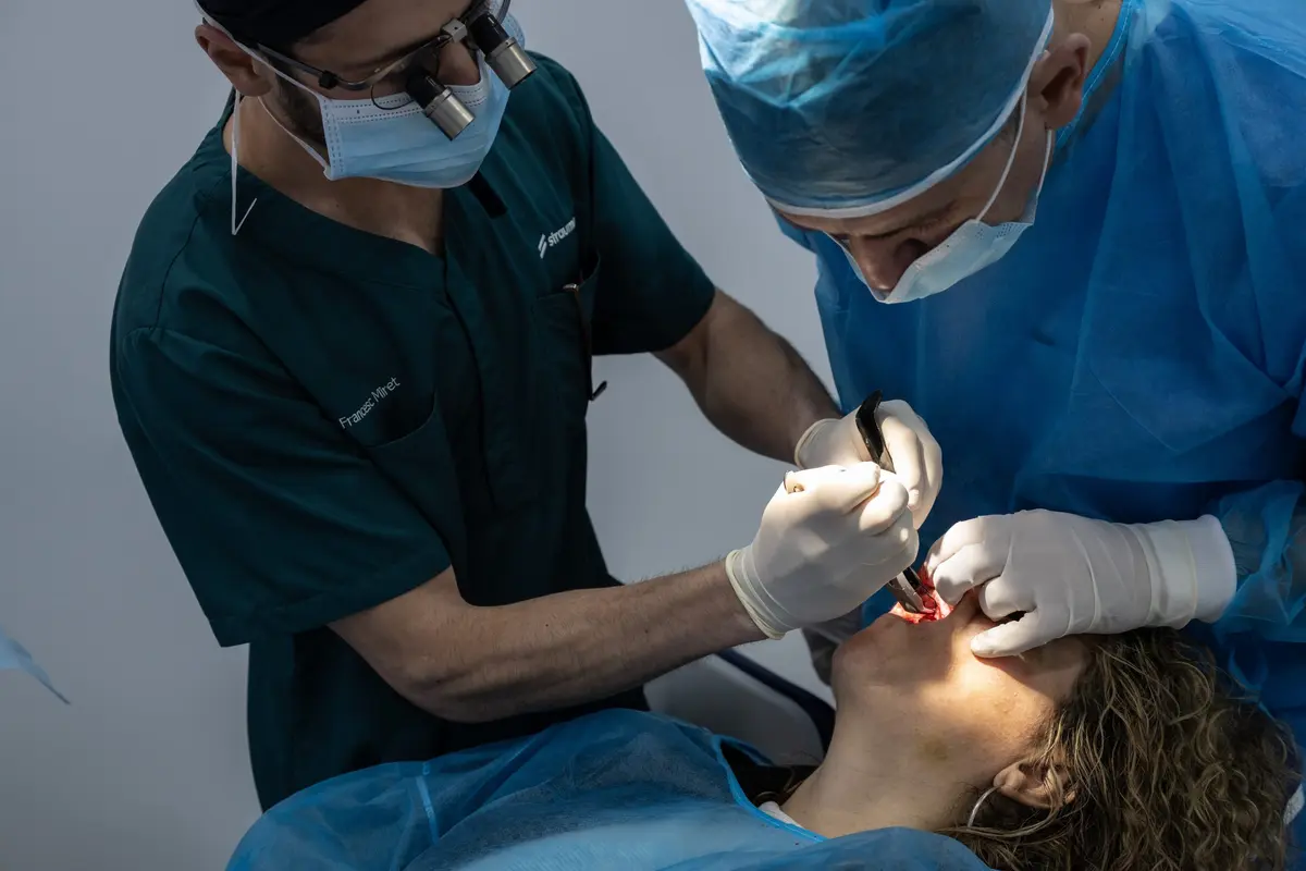 Two surgeons in green scrubs operating on a patient