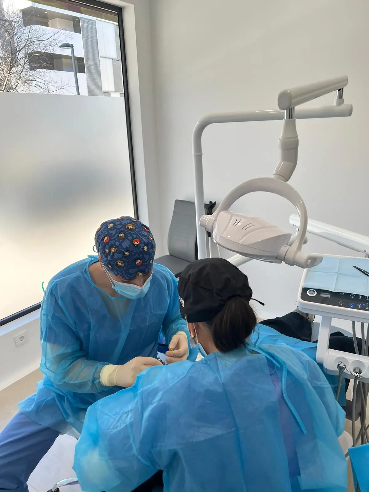 Two clinicians in surgical gowns working side by side on a case
