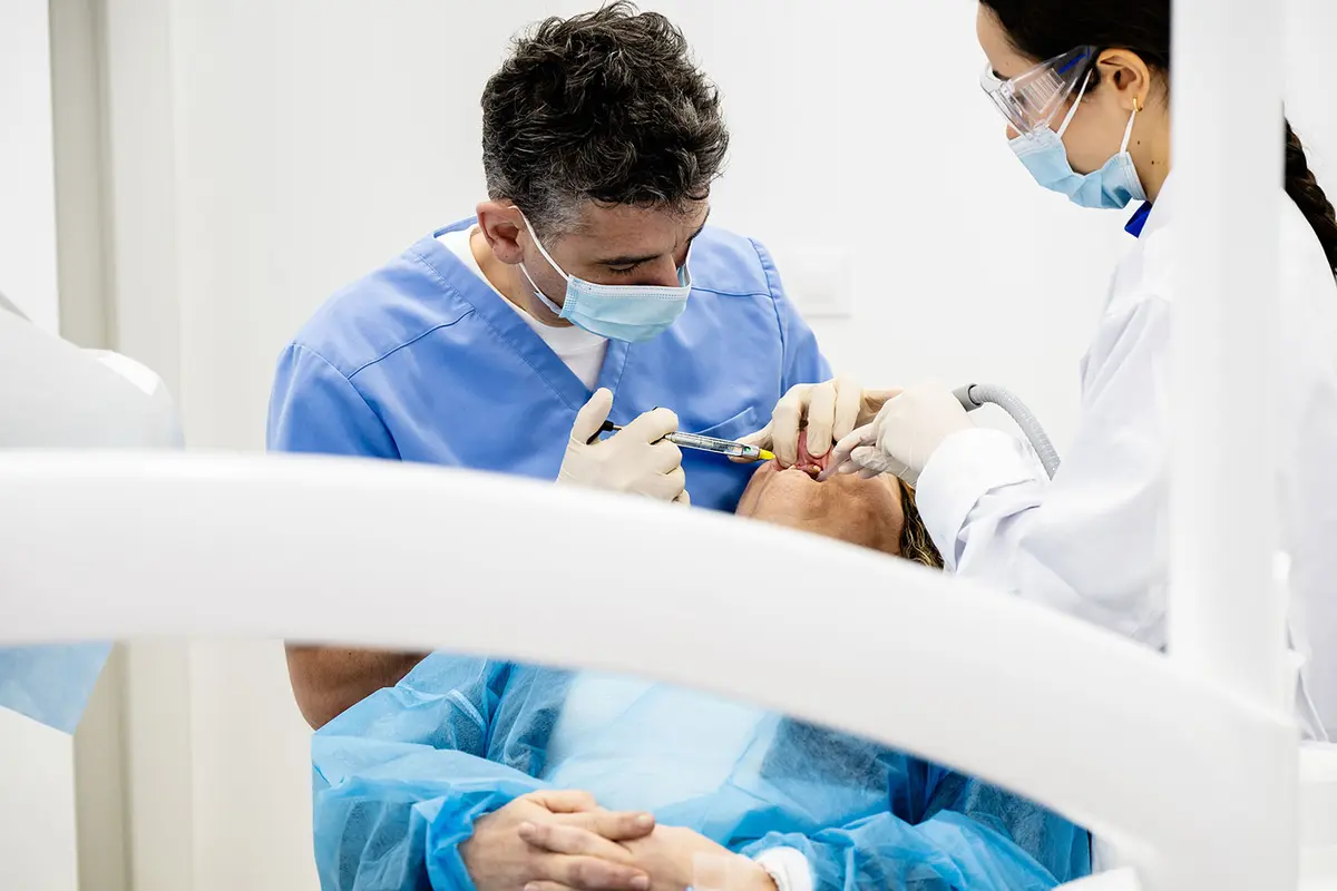 A surgeon and an assistant working on a patient under the surgical light