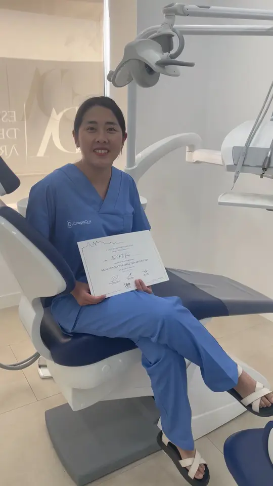 A clinician sitting in the clinic, holding the course certificate