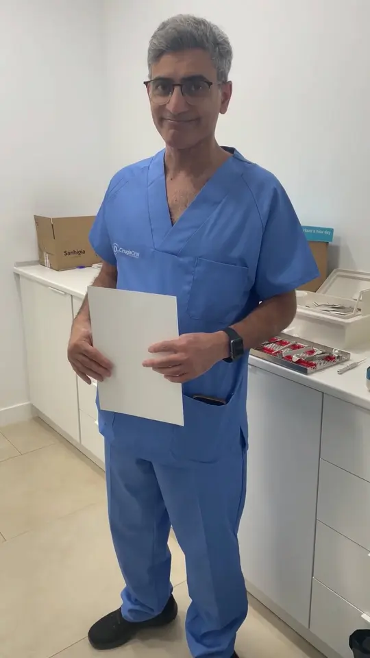 A clinician sitting in the clinic, holding the course certificate