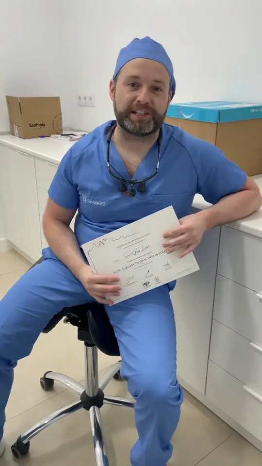 A clinician sitting in the clinic, holding the course certificate