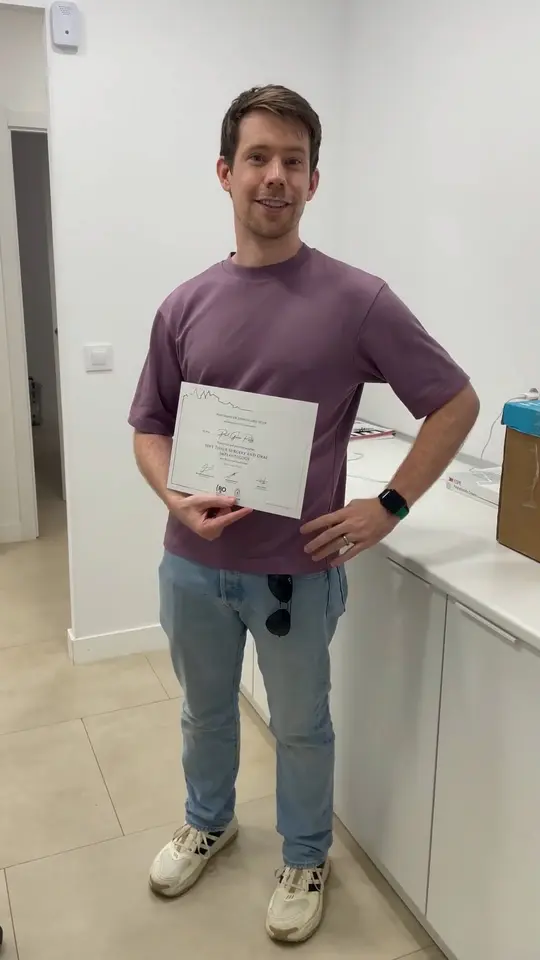 A clinician sitting in the clinic, holding the course certificate